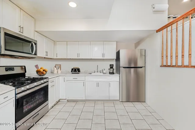 a kitchen with white cabinets a sink stove and refrigerator