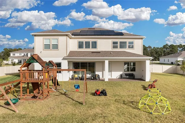 a view of a white house with swimming pool lawn chairs and a barbeque