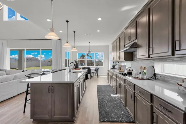 a kitchen with stainless steel appliances granite countertop a sink a stove and a wooden floors