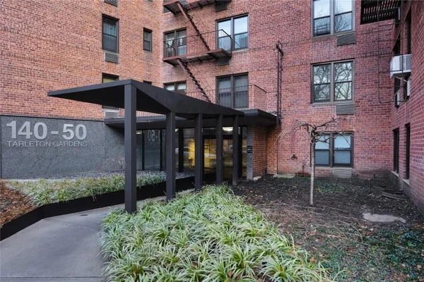 front view of a brick house with a small yard and a table and chairs