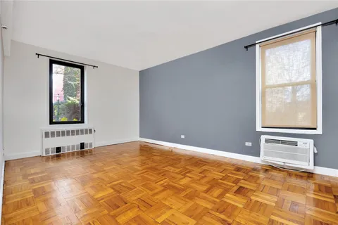 a view of an empty room with window and wooden floor