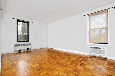 a view of an empty room with window and wooden floor