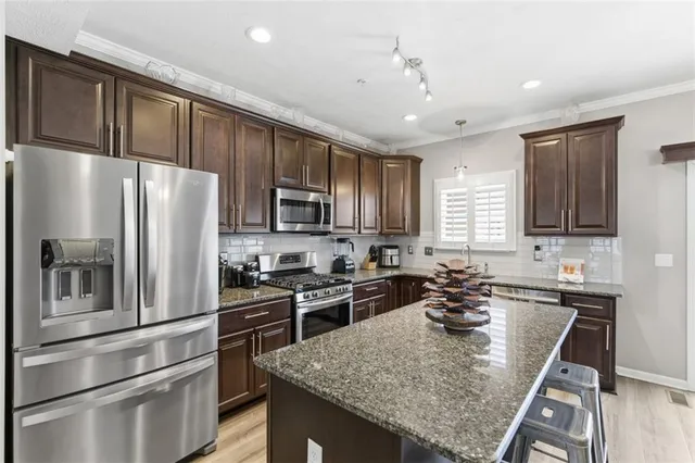 a kitchen with granite countertop a refrigerator stove and sink