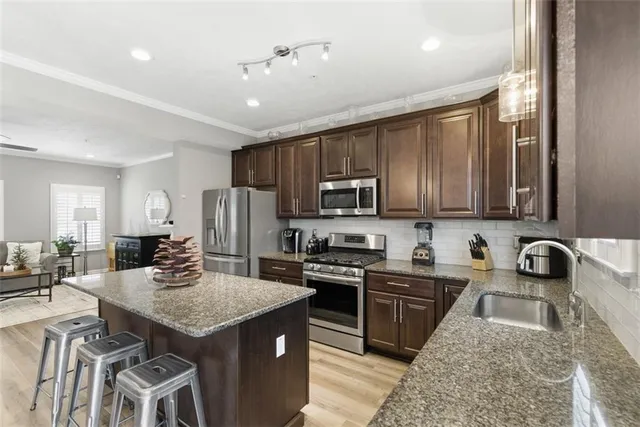 a kitchen with stainless steel appliances granite countertop a sink stove microwave and refrigerator