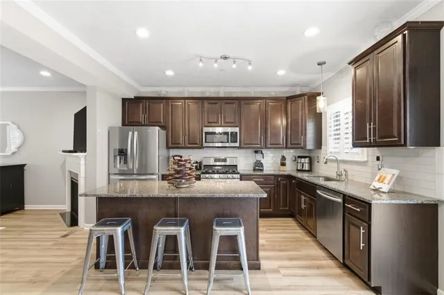 a kitchen with stainless steel appliances granite countertop wooden cabinets a refrigerator and a stove top oven