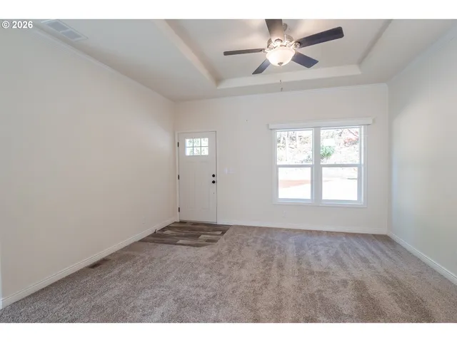 a view of an empty room with a ceiling fan and window