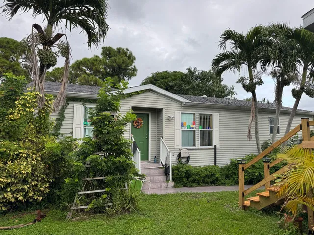 a front view of a house with a yard and potted plants