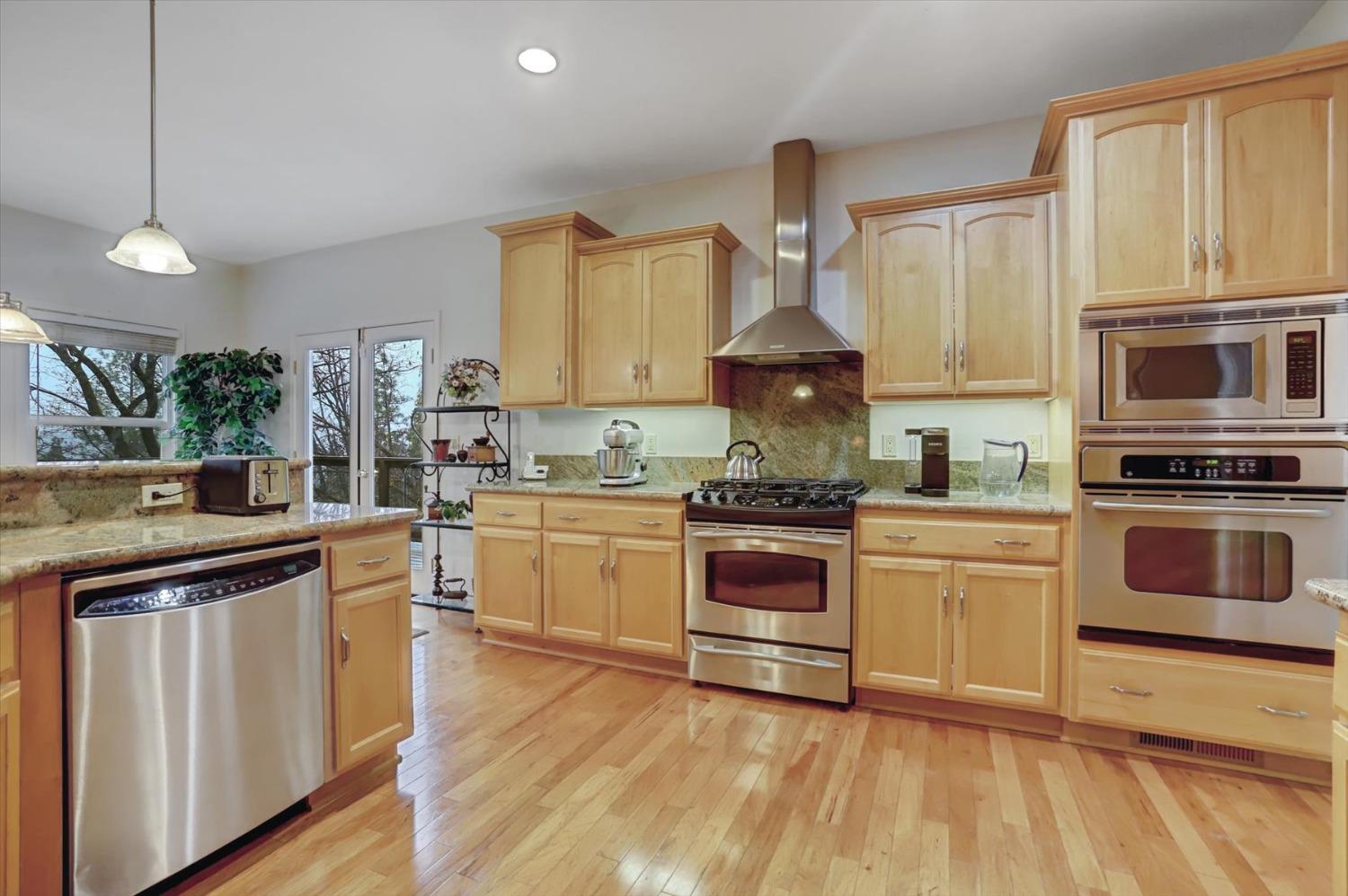 17036 Alice Way Grass Valley, CA 95949 - Photo 3 of 58 a kitchen with granite countertop a stove top oven a sink dishwasher and white cabinets with wooden floor