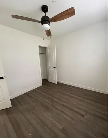 a view of a room with wooden floor a ceiling fan and window