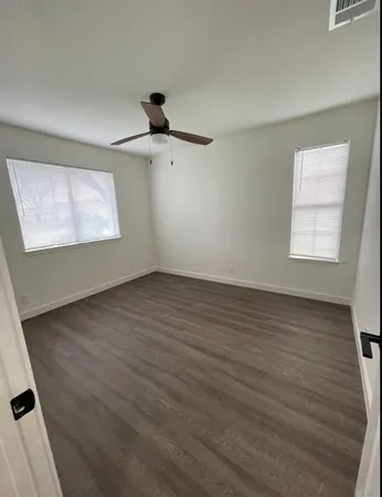 an empty room with wooden floor and windows