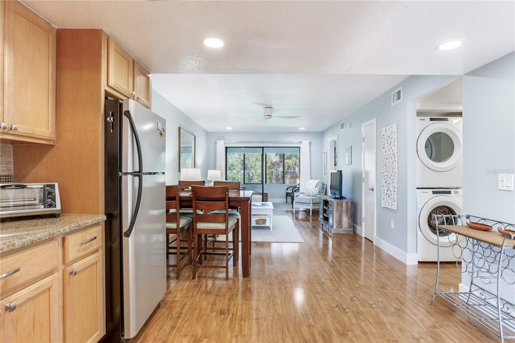 12900 Vonn Road, Unit A204 Largo, FL 33774 - Photo 23 of 40 a kitchen with stainless steel appliances granite countertop a stove top oven a refrigerator a dining table and chairs with wooden floor