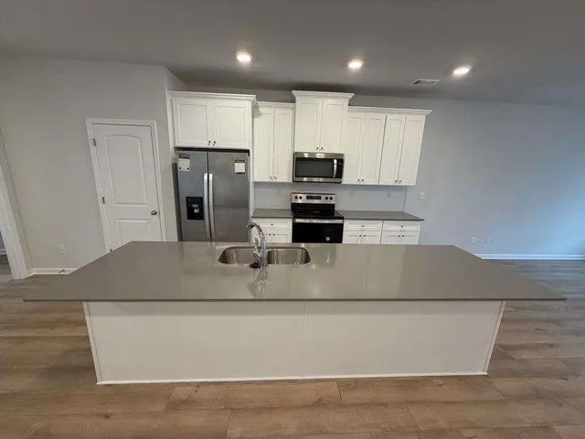 a large kitchen with kitchen island a sink and a stove top oven with wooden floor