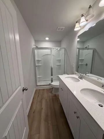 a spacious bathroom with a double vanity sink a mirror and a shower