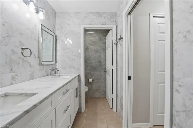 a bathroom with a granite countertop double vanity sink mirror and shower