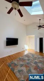 a view of an empty room and kitchen space with wooden floor