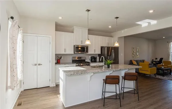 a view of a kitchen with kitchen island stainless steel appliances refrigerator stove dining table and chairs