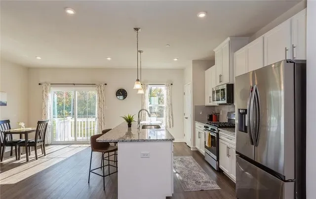 a kitchen with sink a refrigerator and chairs