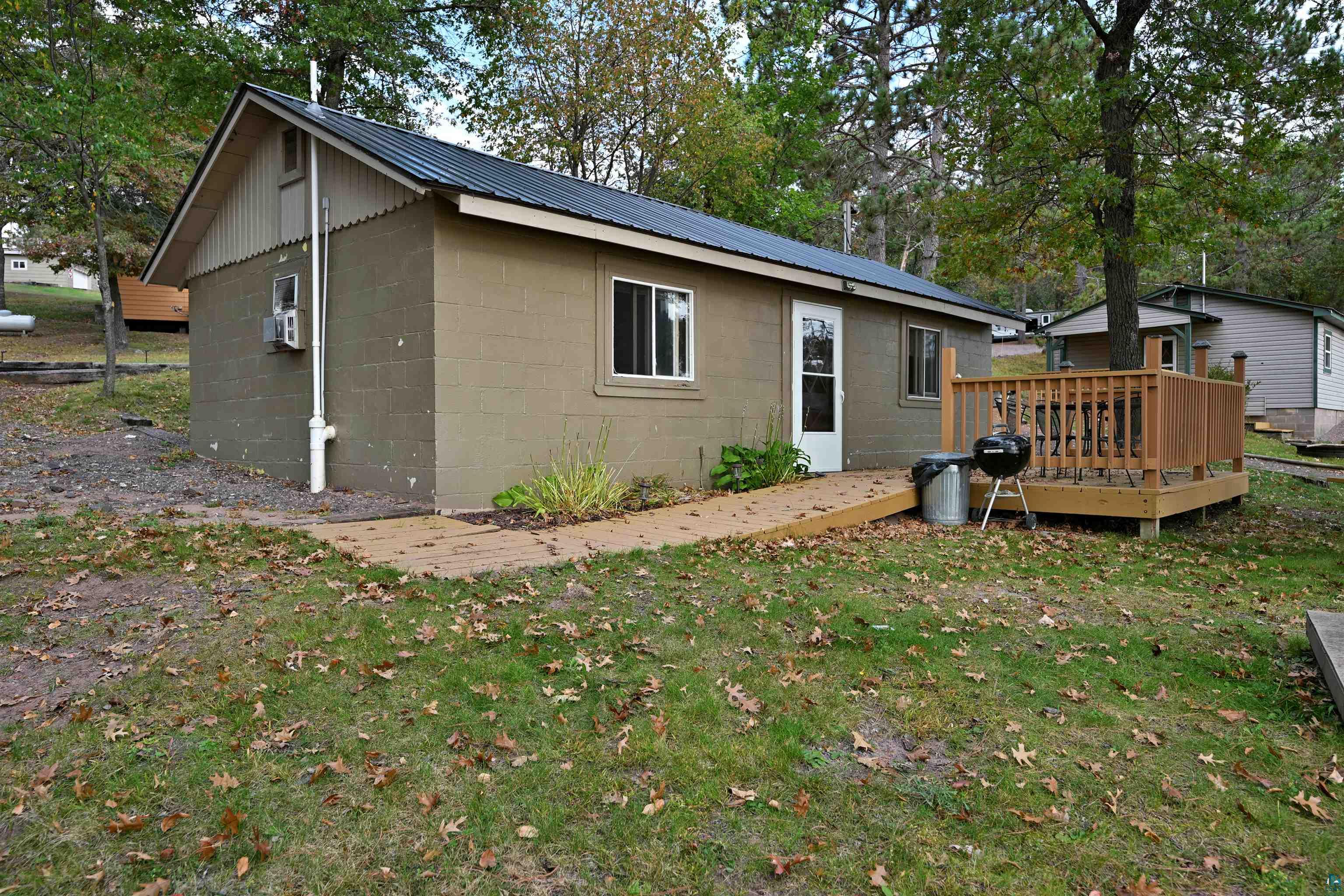 Rear view of property with a yard, a metal roof, concrete block siding, and a wooden deck