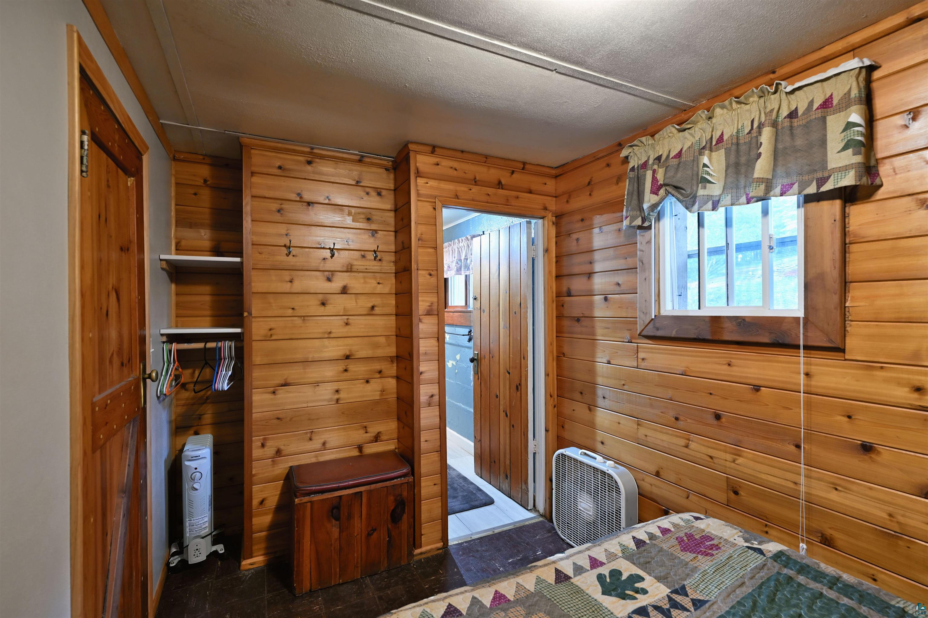 6833 View Point Lodge Road, Unit 13 Gordon, WI 54838 - Photo 11 of 32 Bedroom featuring wood walls, ensuite bath, and a textured ceiling