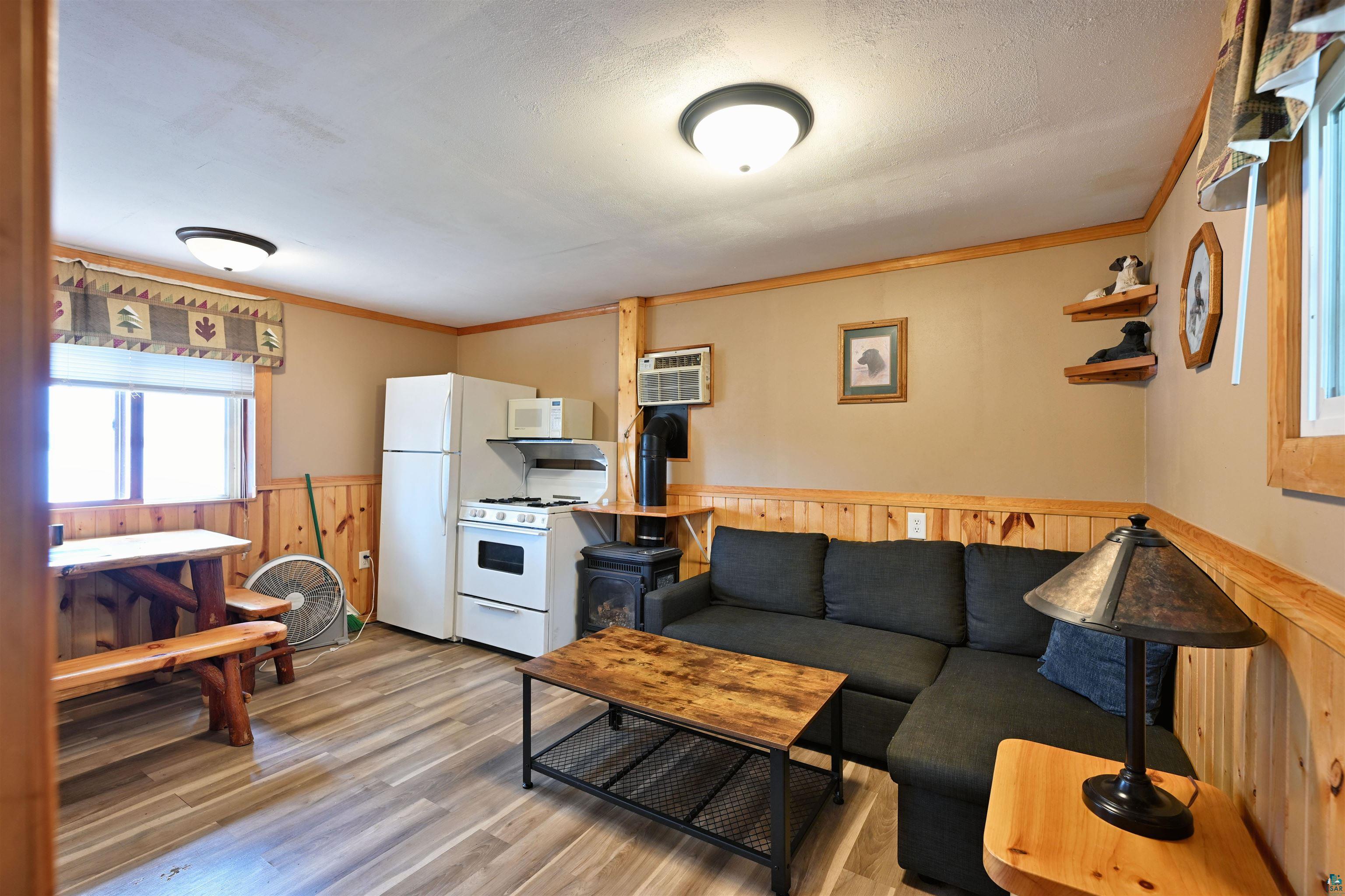 6833 View Point Lodge Road, Unit 13 Gordon, WI 54838 - Photo 15 of 32 Living area with crown molding, wainscoting, wooden walls, light wood-style flooring, and a wood stove