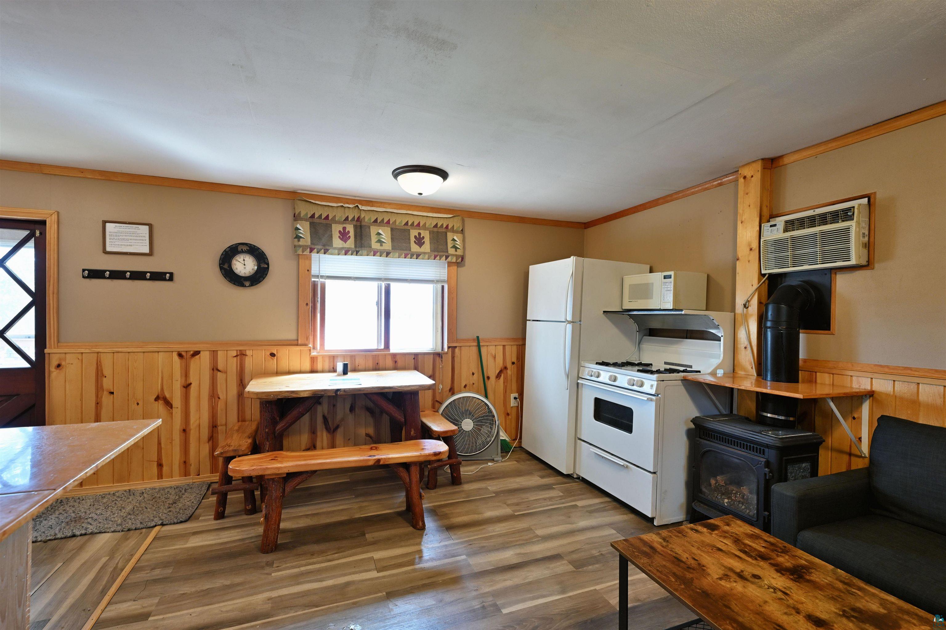 6833 View Point Lodge Road, Unit 13 Gordon, WI 54838 - Photo 16 of 32 Kitchen with wainscoting, wood walls, white appliances, a wood stove, and crown molding