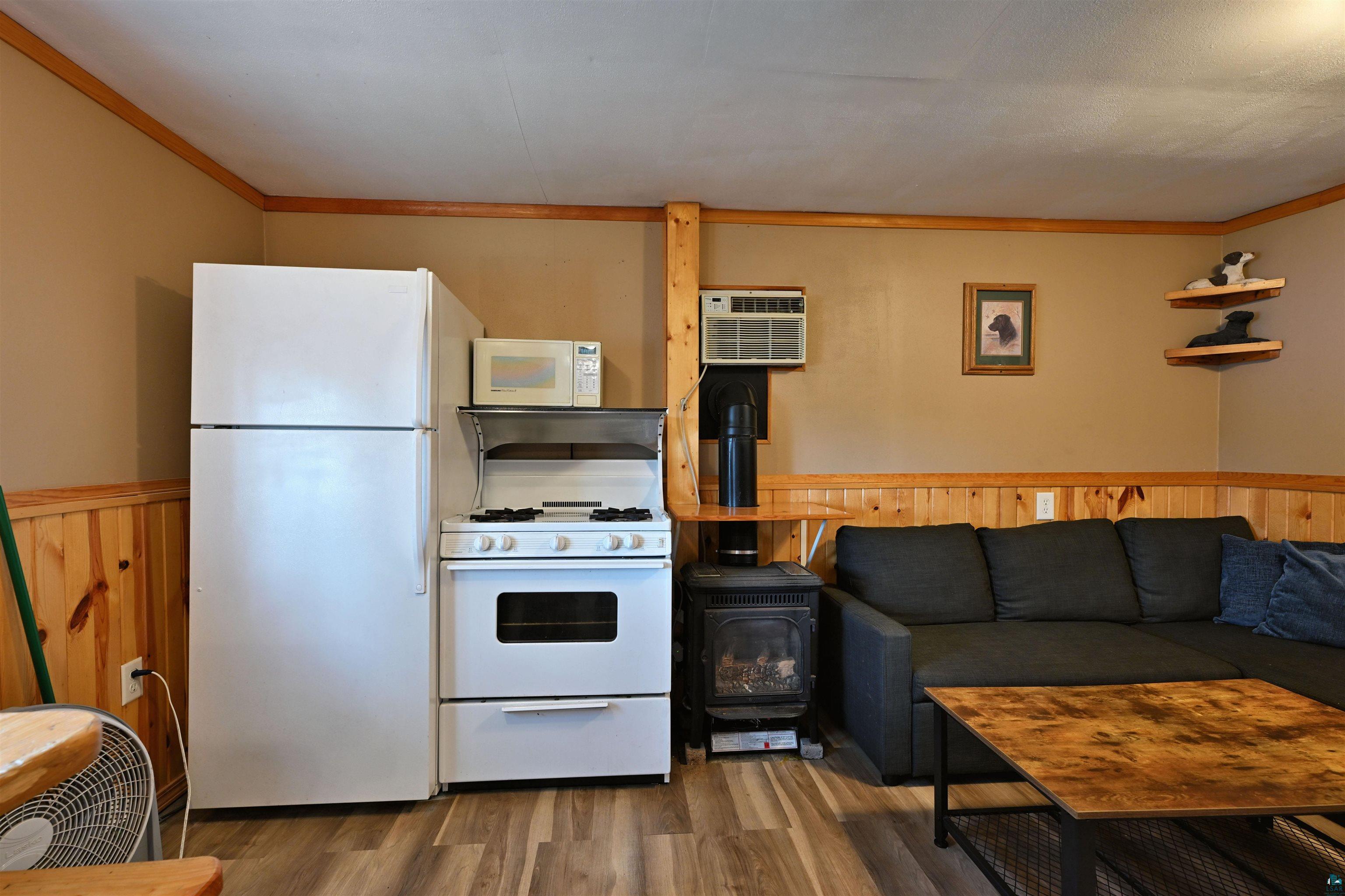 6833 View Point Lodge Road, Unit 13 Gordon, WI 54838 - Photo 18 of 32 Kitchen with white appliances, a wood stove, wainscoting, wood finished floors, and wooden walls