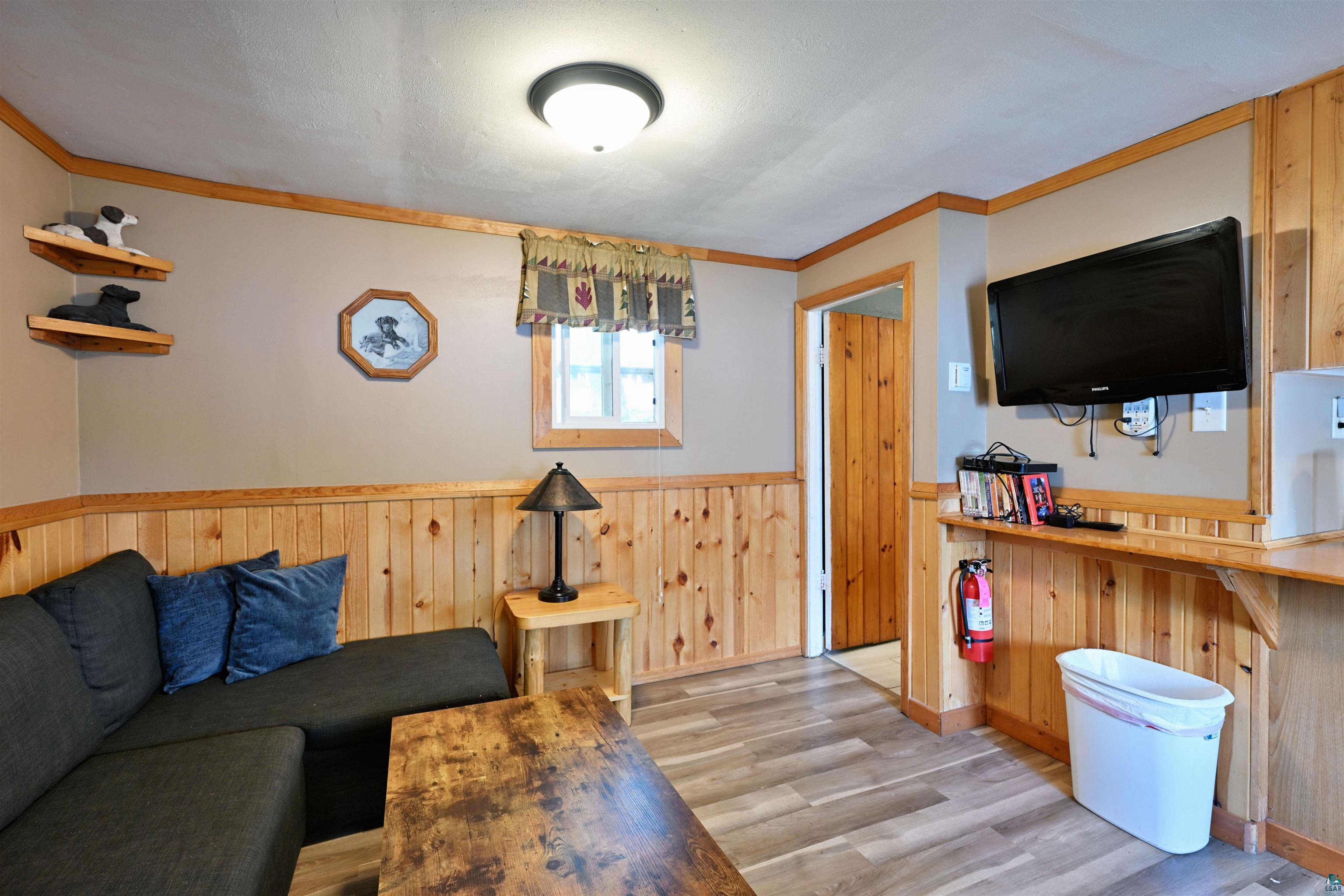 6833 View Point Lodge Road, Unit 13 Gordon, WI 54838 - Photo 21 of 32 Living room with wainscoting, crown molding, wood walls, and light wood-type flooring