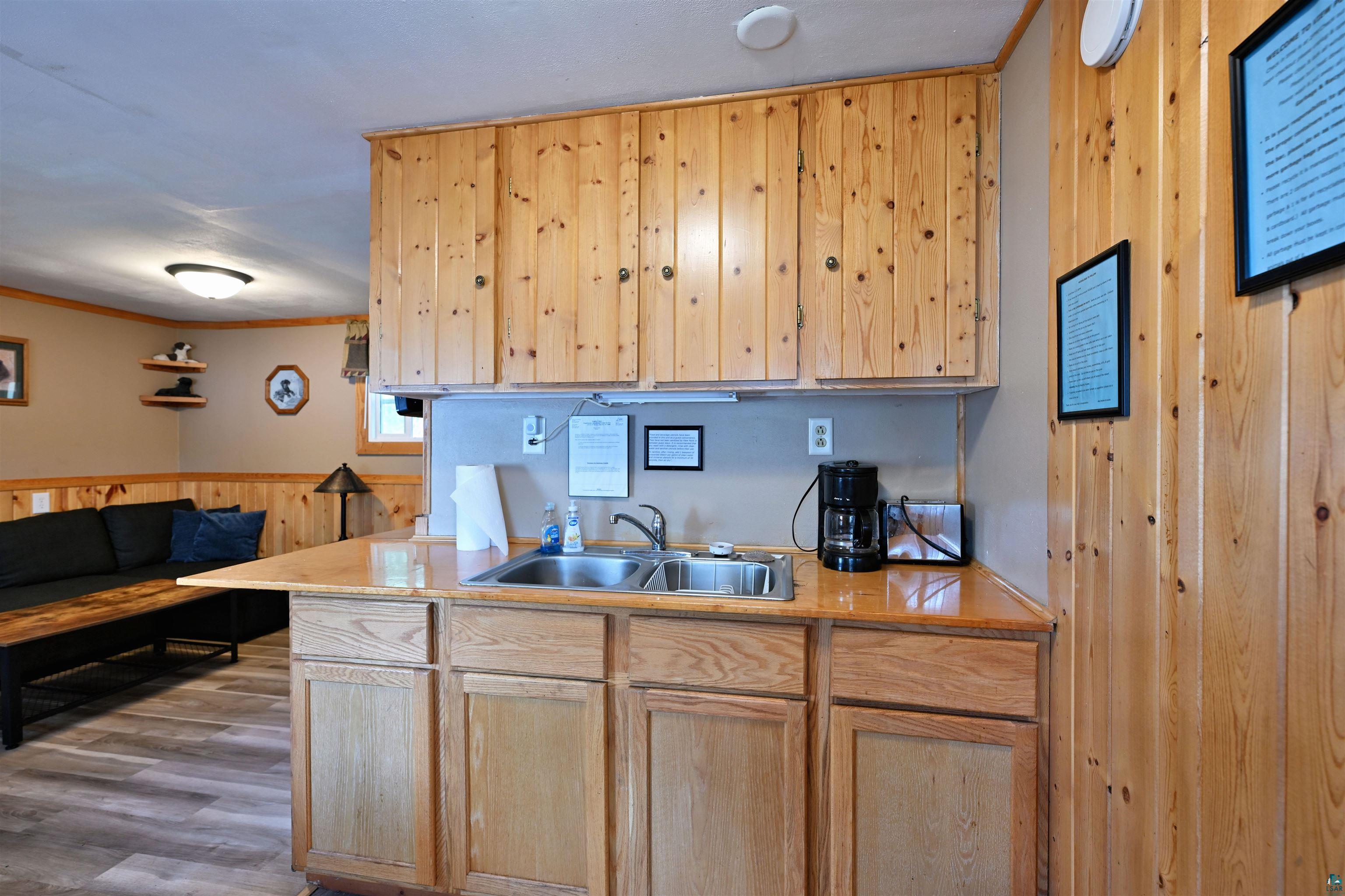 6833 View Point Lodge Road, Unit 13 Gordon, WI 54838 - Photo 22 of 32 Kitchen featuring light wood finish cabinets, wood walls, light countertops, ornamental molding, and a wainscoted wall