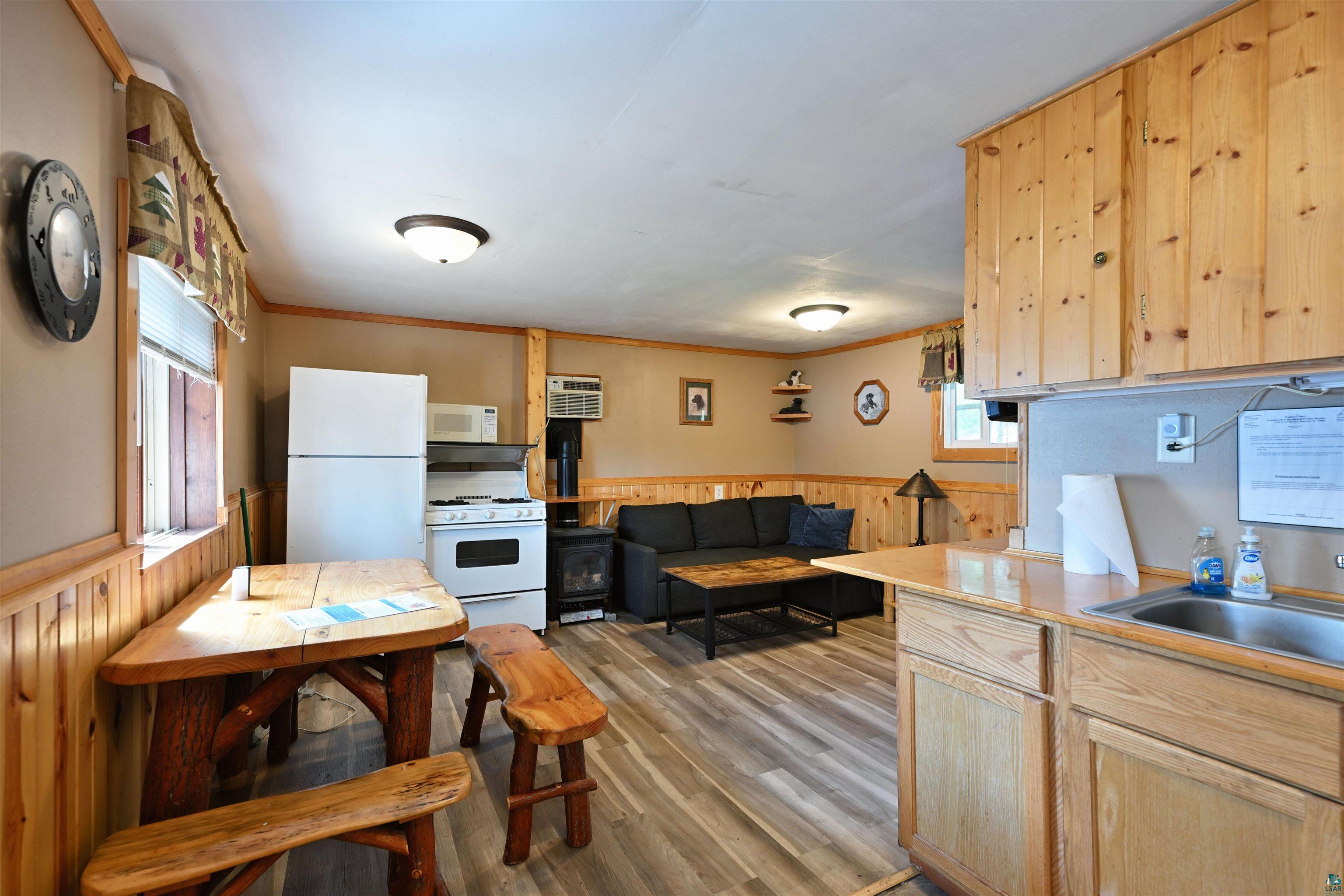 6833 View Point Lodge Road, Unit 13 Gordon, WI 54838 - Photo 23 of 32 Kitchen with light wood finish cabinets, a wainscoted wall, wood walls, white appliances, and light countertops