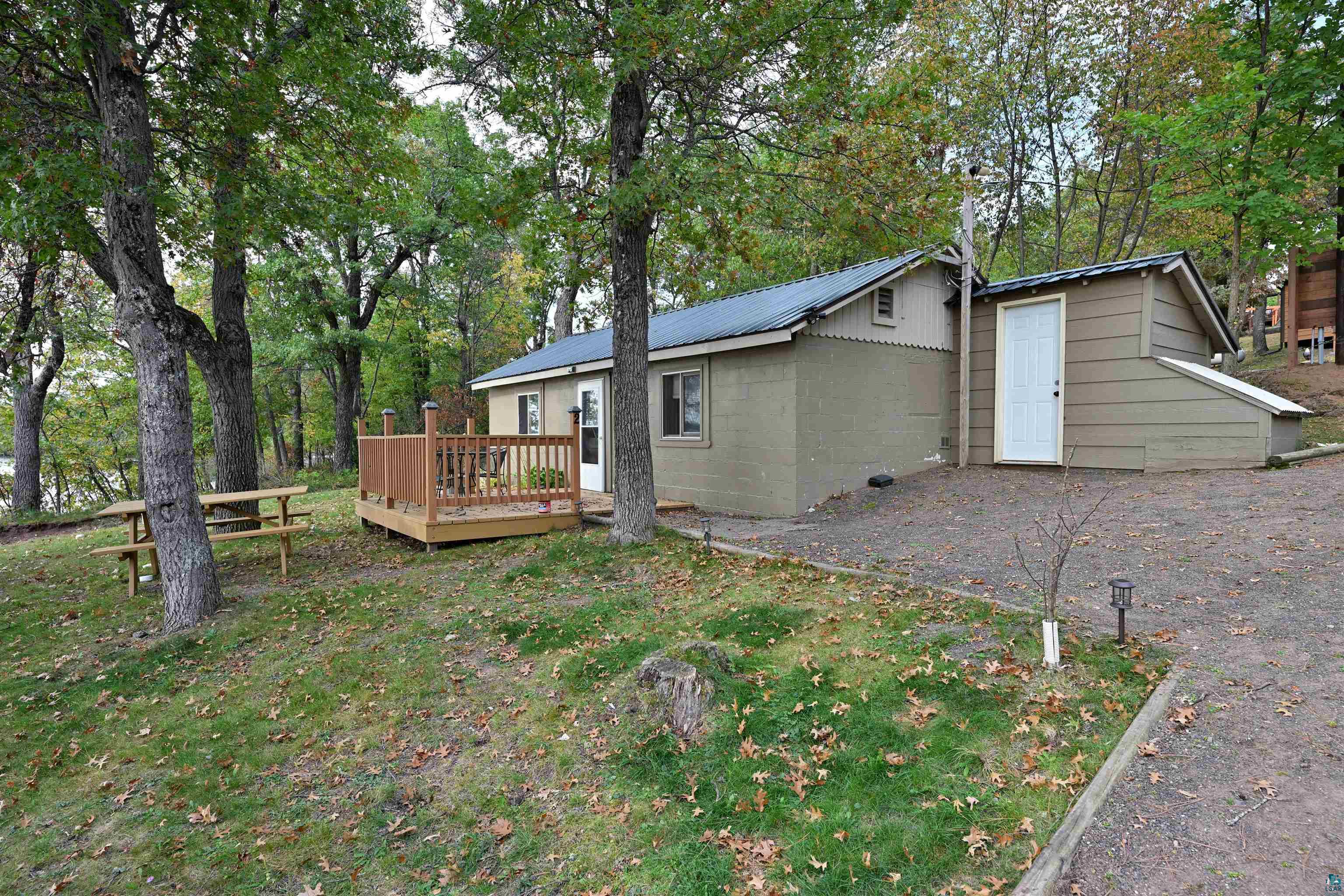 6833 View Point Lodge Road, Unit 13 Gordon, WI 54838 - Photo 31 of 32 Back of house featuring concrete block siding, a metal roof, view of scattered trees, a lawn, and a deck