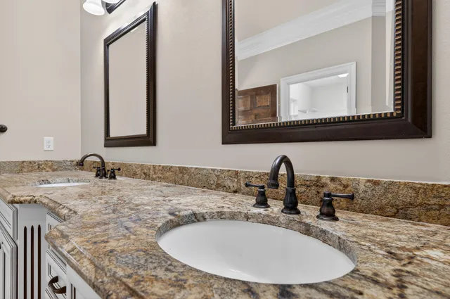 a view of a white house next to a yard with a large tree