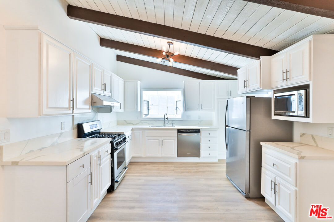 20341 Enadia Way Winnetka, CA 91306 - Photo 6 of 23 a kitchen with a sink a refrigerator and white cabinets