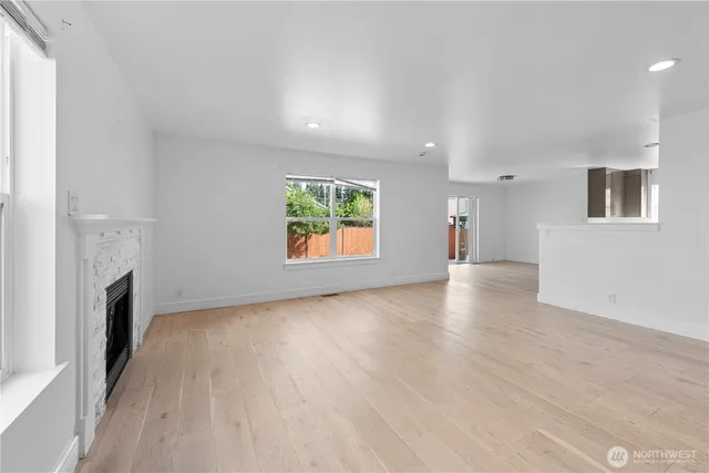 an empty room with windows and fireplace