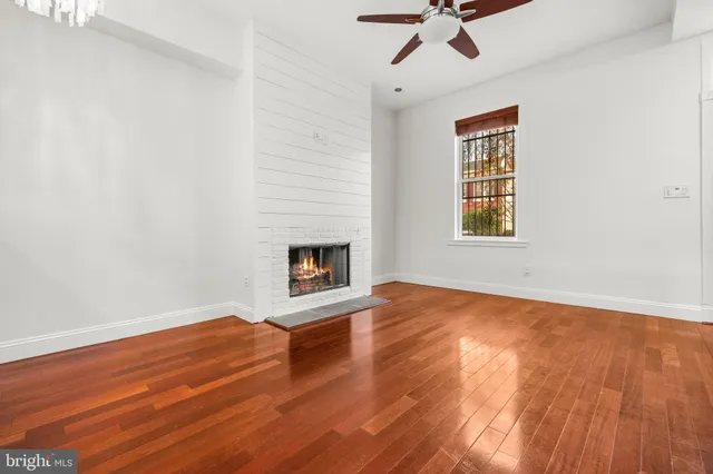 an empty room with wooden floor fireplace and windows