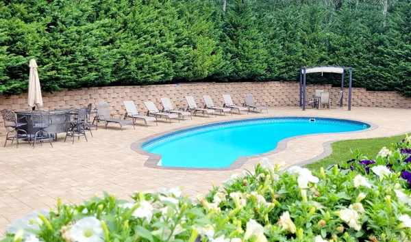 a view of a swimming pool with lawn chairs under an umbrella