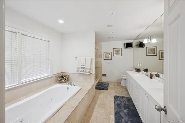 a spacious bathroom with a tub sink and mirror