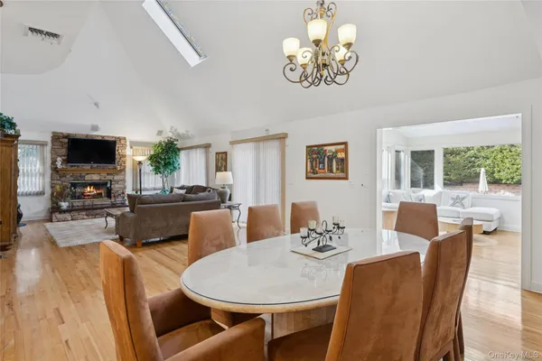 a dining room with furniture a kitchen wooden floor and a chandelier
