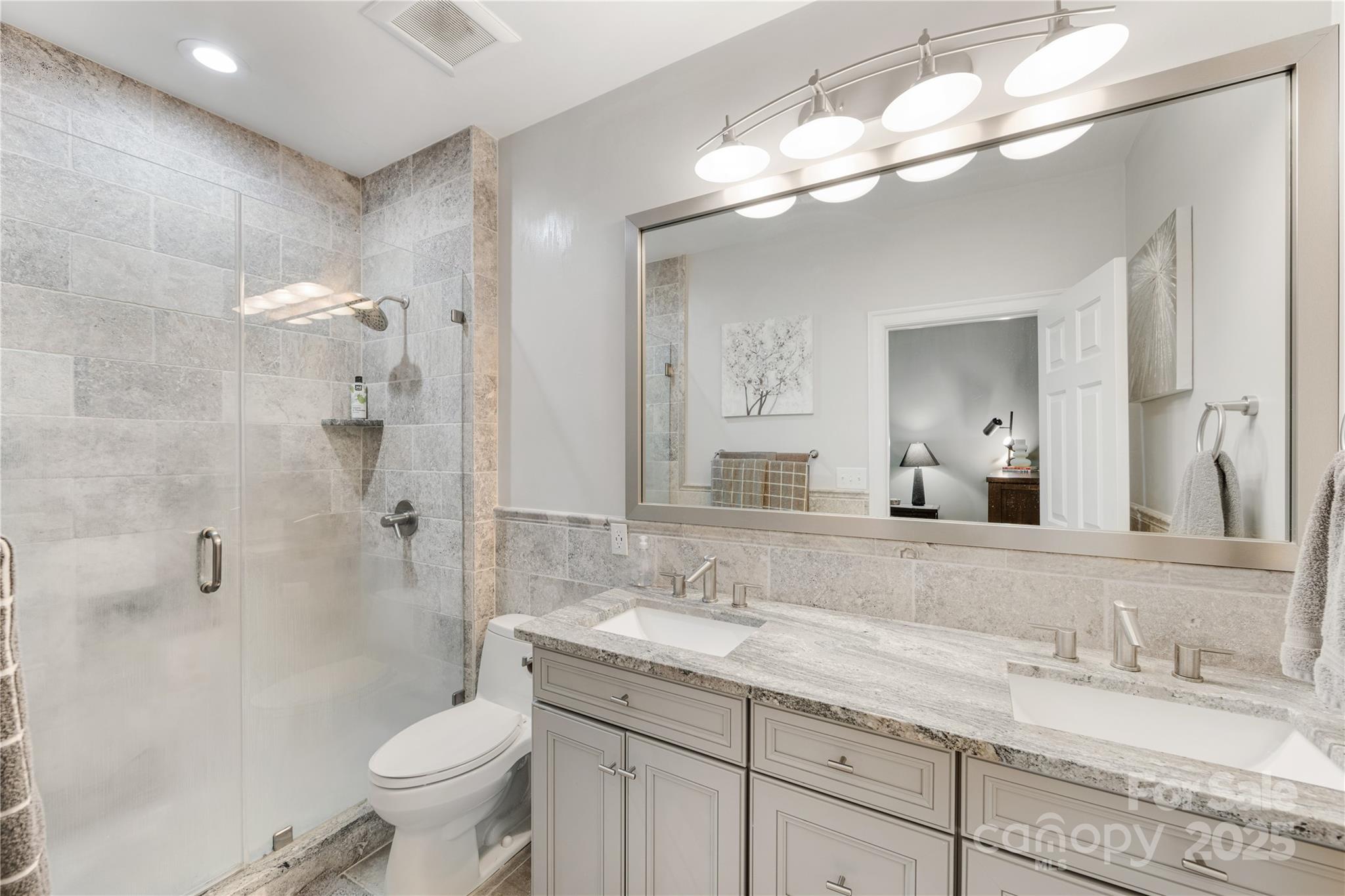127 North Tryon Street, Unit 511 Charlotte, NC 28246 - Photo 19 of 32 a bathroom with a granite countertop sink a toilet and a mirror
