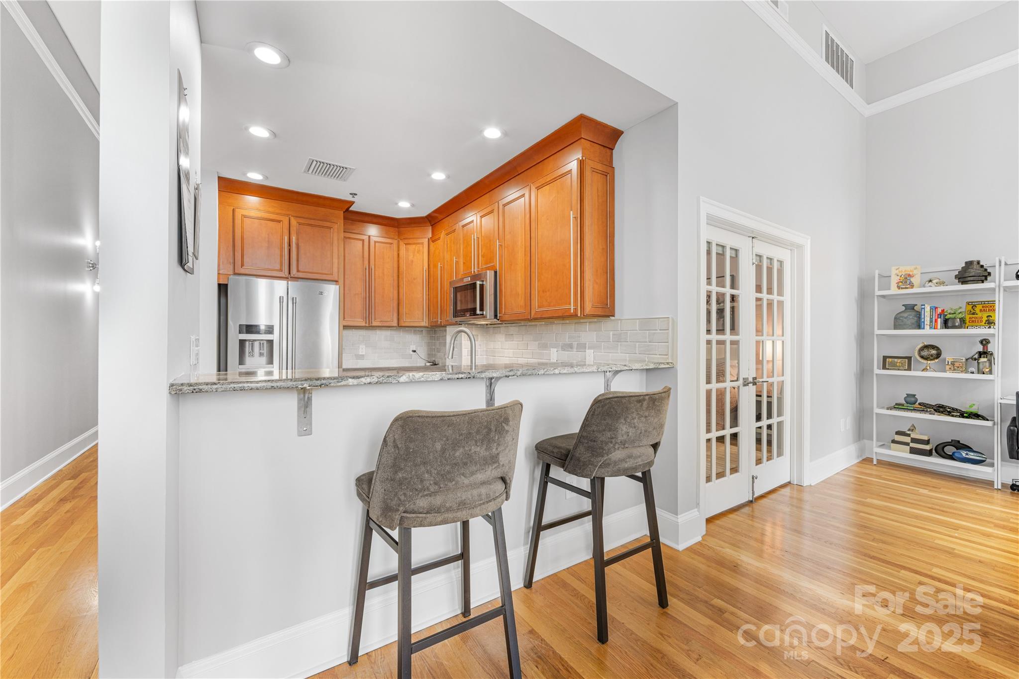127 North Tryon Street, Unit 511 Charlotte, NC 28246 - Photo 9 of 32 a kitchen with stainless steel appliances granite countertop a stove top oven a dining table and chairs with wooden floor