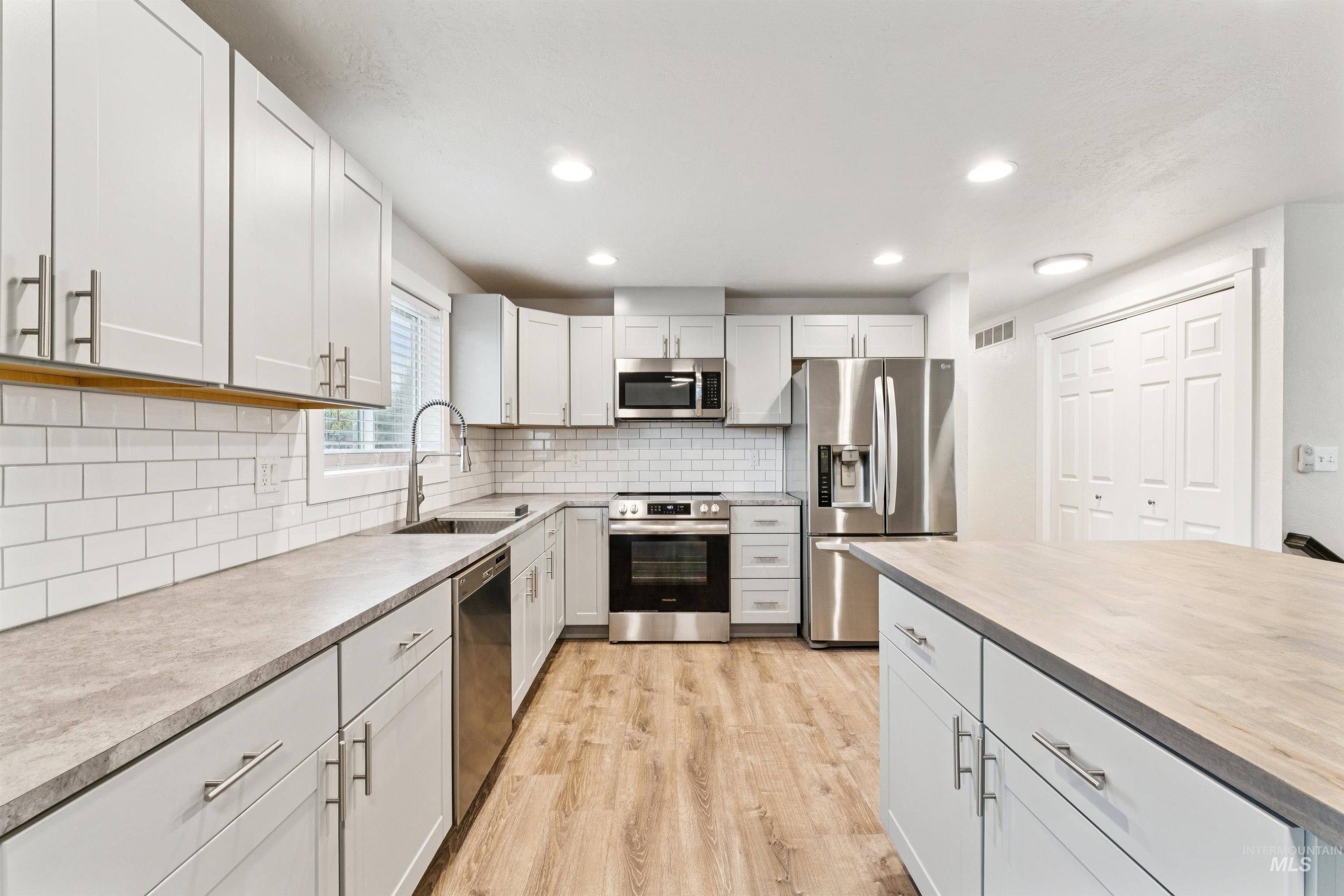 4811 North Leather Way Boise, ID 83713 - Photo 10 of 32 Kitchen with stainless steel appliances, backsplash, recessed lighting, light wood-type flooring, and butcher block countertops