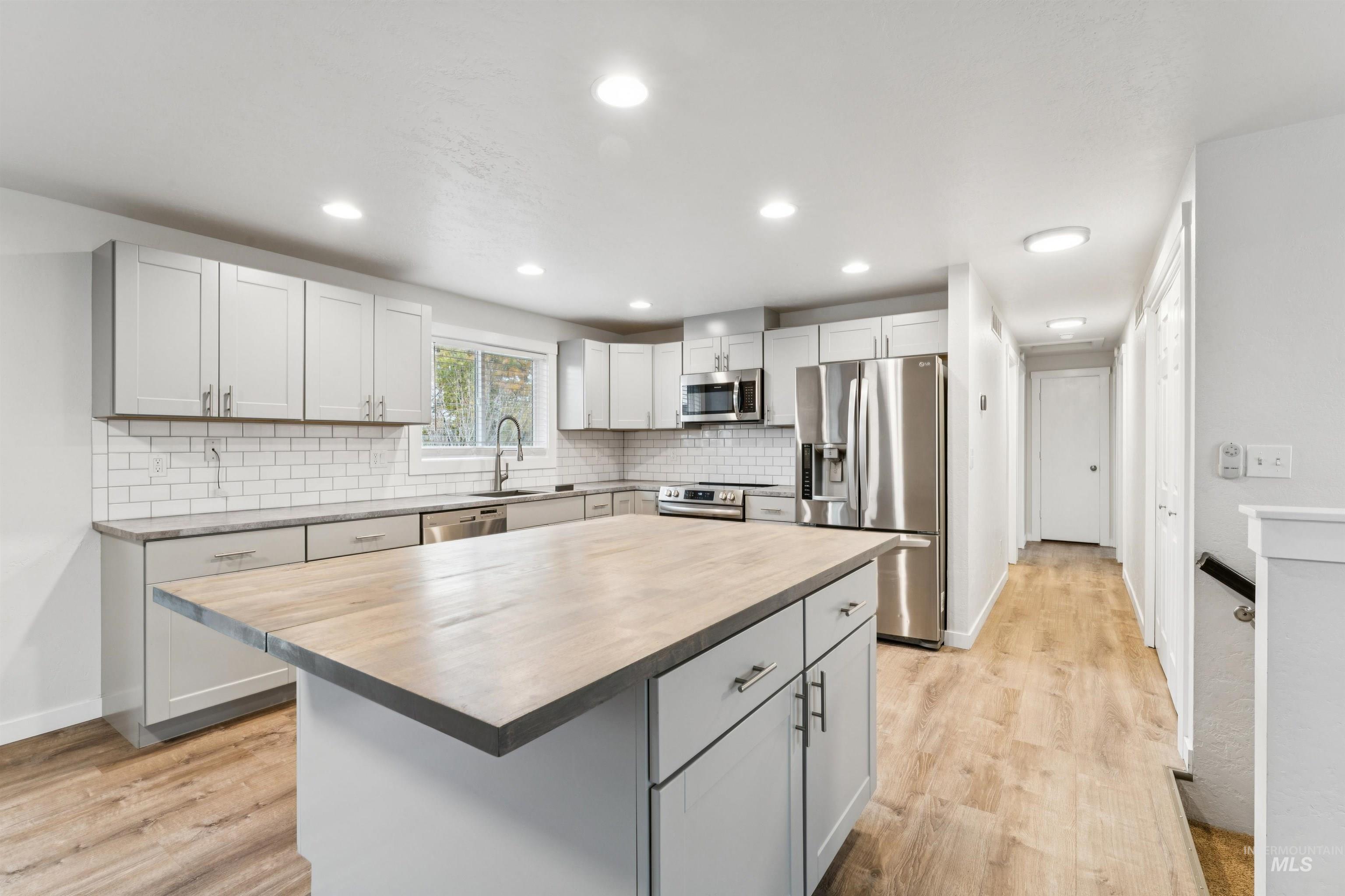 4811 North Leather Way Boise, ID 83713 - Photo 13 of 32 Kitchen with stainless steel appliances, light wood-style flooring, a center island, tasteful backsplash, and recessed lighting