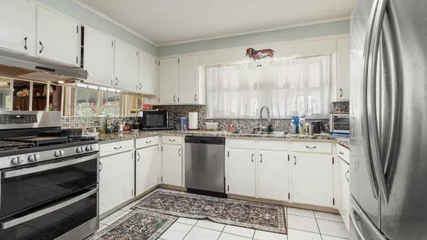 a kitchen with stainless steel appliances granite countertop a refrigerator and a white cabinets
