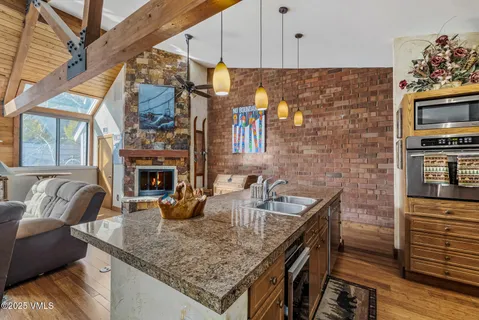 a kitchen with stainless steel appliances granite countertop a sink a stove and a wooden cabinets