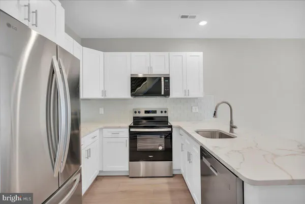 a kitchen with stainless steel appliances granite countertop a refrigerator stove and sink