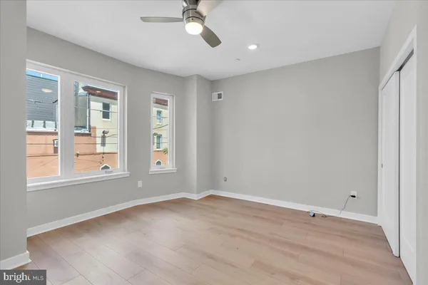 a view of empty room with wooden floor and fan