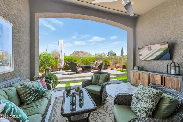 a view of a patio with table and chairs potted plants and a large window