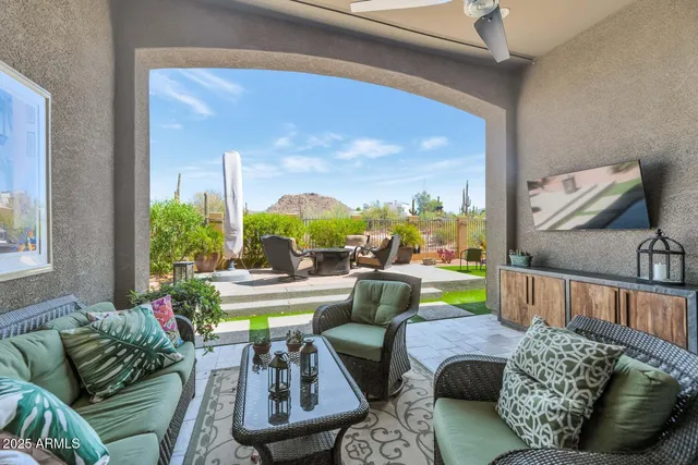 a view of a patio with table and chairs potted plants and a large window
