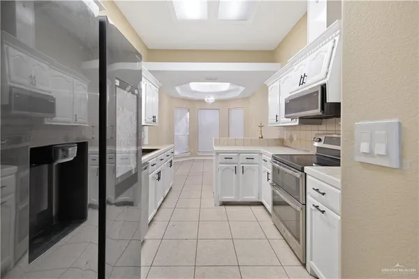 a kitchen with white cabinets and appliances