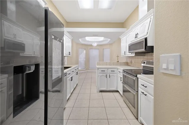 a kitchen with white cabinets and appliances