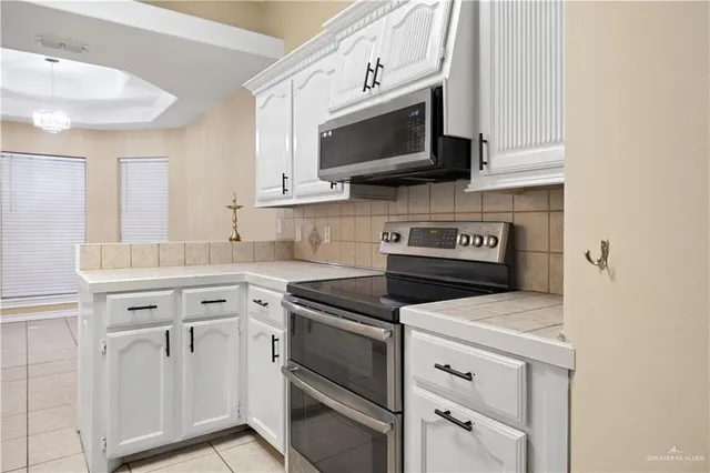 a kitchen with white cabinets and stainless steel appliances